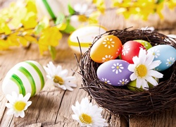 Wielkanocna dekoracja z pisankami w gnieździe i kwiatami
