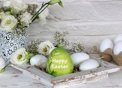 Wielkanocna dekoracja z życzeniami na pisance wśród jajek i kwiatów