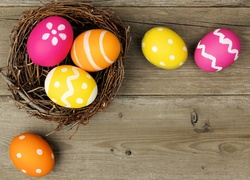 Wielkanocne pisanki w koszyczku i na drewnianym blacie