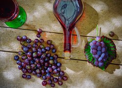 Wino w butelce i kieliszku obok winogron