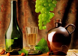 Winogrona i kieliszek z winem pomiędzy butelką i karafką