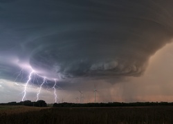 Wir tornada z błyskawicami nad polem z wiatrakami