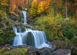 Wodospad na skałach otoczony jesiennymi drzewami