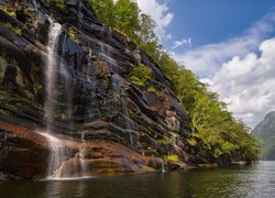 Wodospad na skałach wpadający do norweskiego fiordu Fyksesund