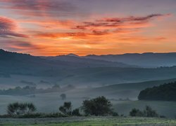 Wschód słońca nad zamgloną doliną Val dOrcia w Toskanii