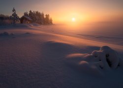 Wschód słońca nad zamglonym i zaśnieżonym jeziorem