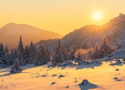 Wschód słońca nad zamglonymi górami zimową porą