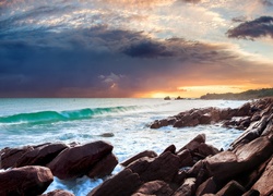 Zachmurzone niebo nad wzburzonym morzem i skałami przy brzegu