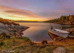 Zachód słońca nad jeziorem z łódką przy brzegu