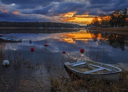Zachód słońca nad jeziorem z zacumowanymi łódkami