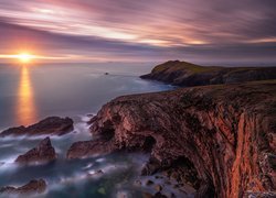 Zachód słońca nad skalistym wybrzeżem morza w Walii