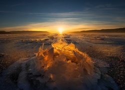Zachód słońca oświetla bryłę lodu na jeziorze