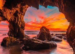 Zachód słońca widziany ze skalnej jaskini na morskim wybrzeżu