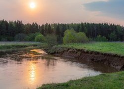 Zachodzące słońce nad rzeką i lasem