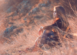 Zadumana dziewczyna siedzi na trawie