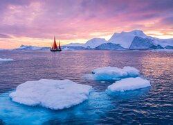 Żaglówka i kry lodowe na morzu w Grenlandii