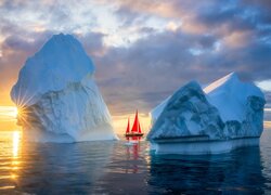 Żaglówka pomiędzy górami lodowymi na morzu