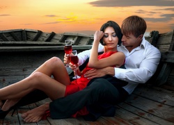 Zakochani w objęciach na łódce piją czerwone wino