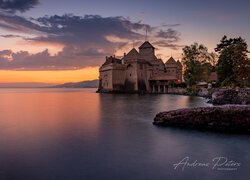 Zamek Chillon nad Jeziorem Genewskim pod niebem zachodzącego słońca