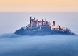 Zamek Hohenzollern na skale i gęsta mgła nad lasami