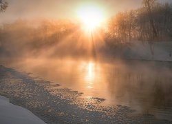 Zamglone słońce nad zamarzniętą rzeką