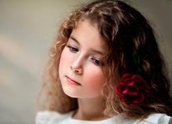 Zamyślona dziewczynka z kwiatkiem we włosach