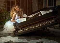 Zamyślona kobieta w białej sukni przy starym zniszczonym fortepianie z nutami