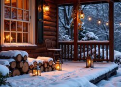 Zapalone lampiony i szczapy drewna na tarasie domu zimową porą