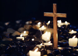 Zapalone świece obok drewnianego krzyża
