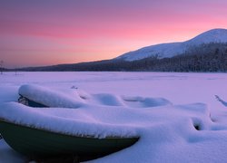Zasypane śniegiem łódki i jezioro w górach