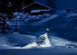Zasypany śniegiem dom w lesie nocą