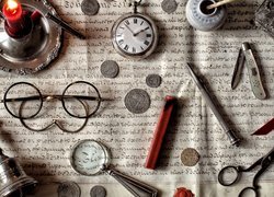 Zegarek, monety i inne drobiazgi rozrzucone na zapisanym papierze