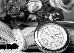 Zegarek obok pereł na tle książki i kwiatów