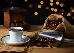 Ziarenka kawy na łopatce obok filiżanki z kawą