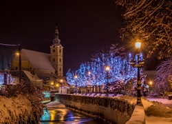 Zimowy widok rzeczki i oświetlonych drzew z kościołem nocą