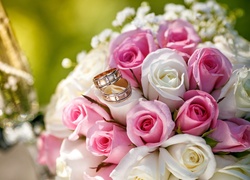 Złote obrączki na ślubnym bukiecie z różowo-białych róż