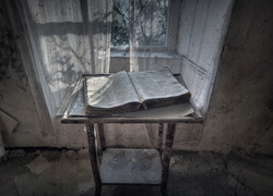 Zniszczona książka na stoliku przy oknie w starym opuszczonym pokoju