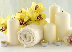 Żółte kwiaty storczyków oraz świeczki i ręczniki w ośrodku SPA