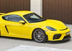 Żółte Porsche 718 Cayman GT4 przed garażem