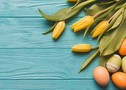 Żółte tulipany i jajka w kompozycji na deskach