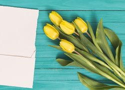 Żółte tulipany obok kartki i koperty