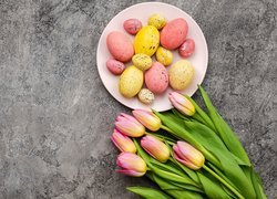 Żółto-różowe tulipany obok pisanek na talerzu