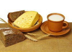 Żółty ser i chleb obok kubka mleka
